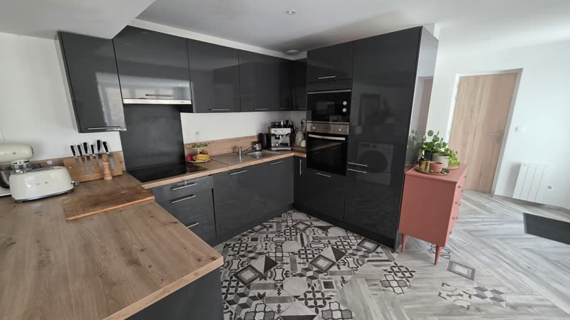 La cuisine équipée, façades noires et plan de travail bois